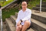 Lydia Pingel, former AFLW player, sitting on stairs looking seriously into camera