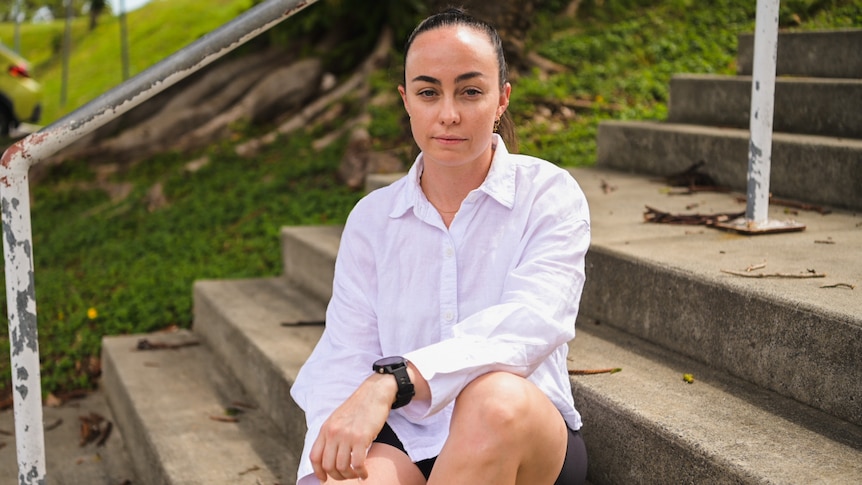 Lydia Pingel, former AFLW player, sitting on stairs looking seriously into camera