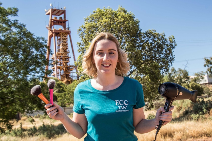 Hairdresser holding scissors in front of a mining headframe