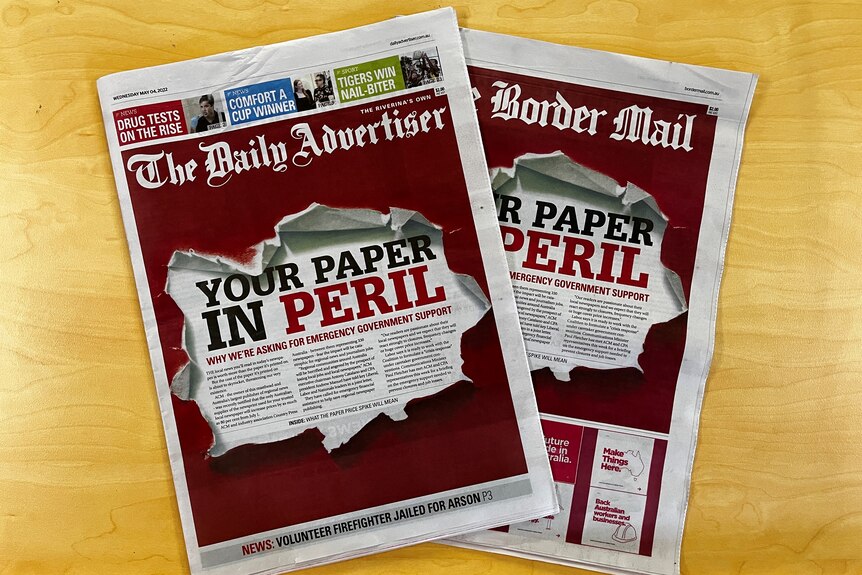 Two regional newspapers featuring the headline "Your paper is in peril" lying on a table.