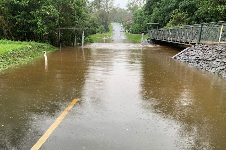 Water over the road with sign reading Pullenvale Creek.