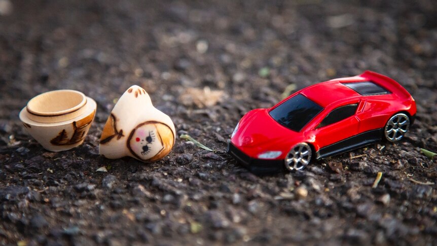 A toy car with a babushka doll that is in pieces.