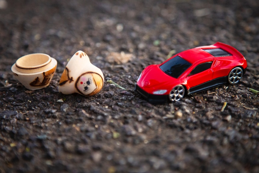 A toy car with a babushka doll that is in pieces.