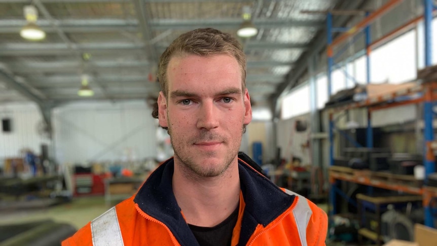 Jake Hartshorn, wearing high-visibility clothing, stands in a factory.