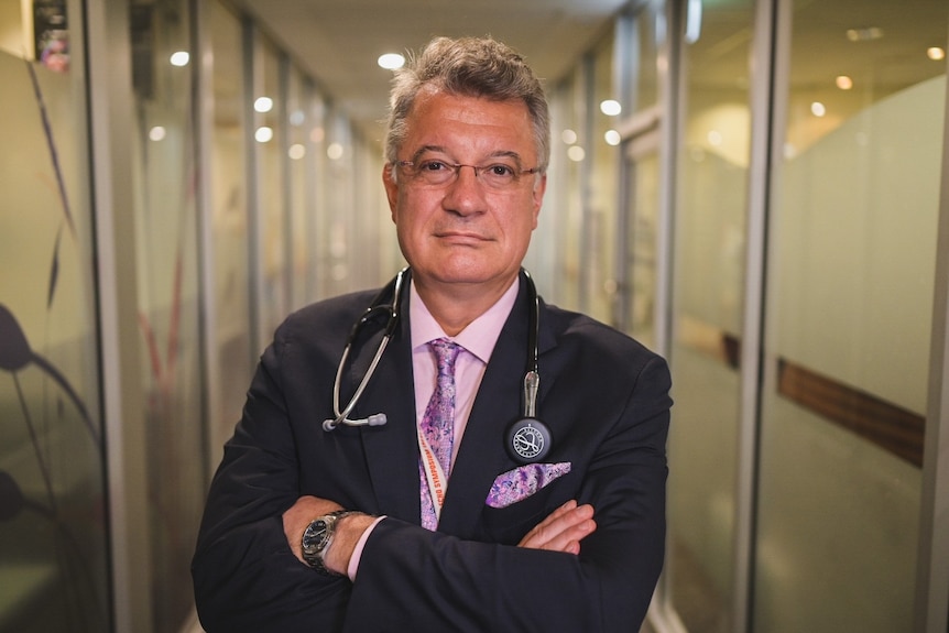 Mater cardiologist Dr Mugur Nicolae stands in a hospital hallway with his arms folded in Brisbane.