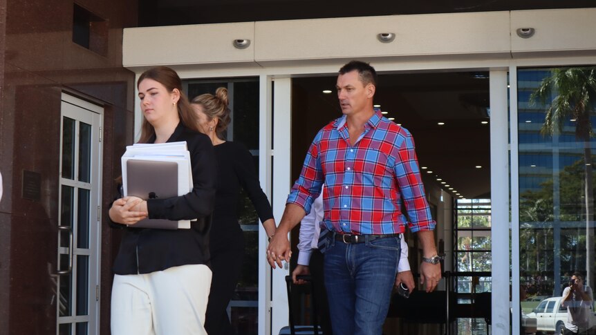 A photo showing a man leaving court holding a woman's hand
