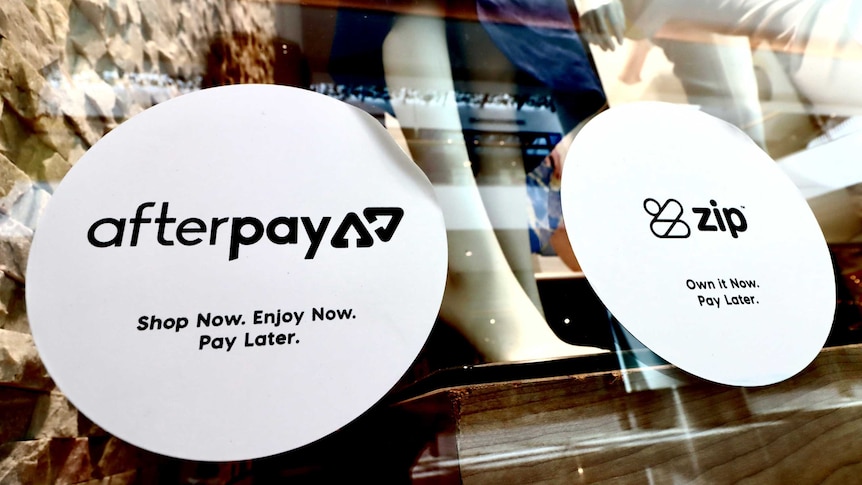 Stickers advertising Afterpay and Zip on the window of a clothing store.