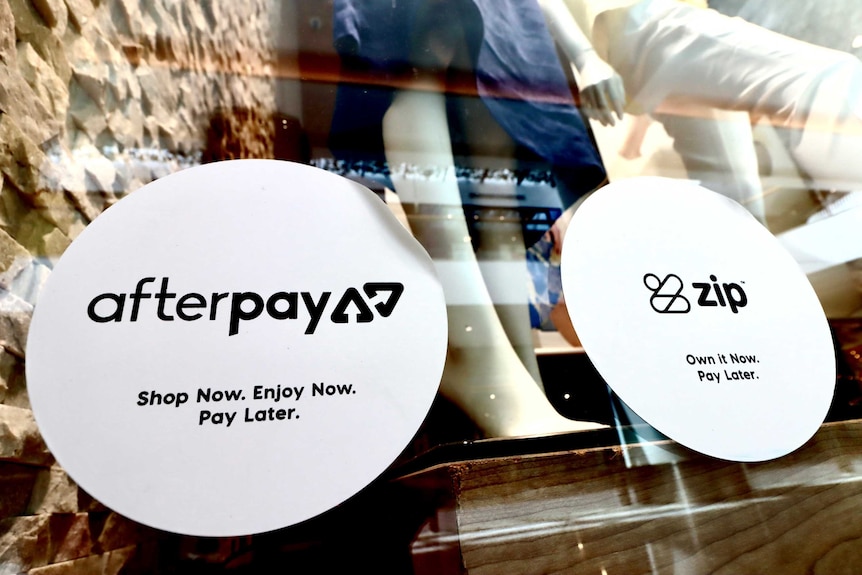 Stickers advertising Afterpay and Zip on the window of a clothing store.