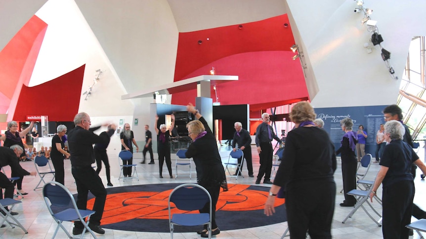 Dancers in a circle improvising in the foyer of the National Museum of Australia.