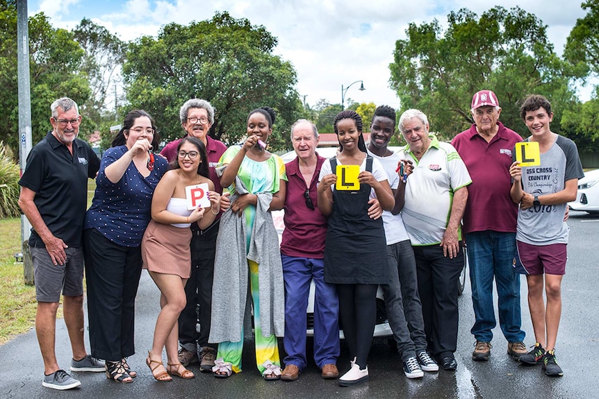 Group of driving teachers and young people smiling and holding up their L and P-plates in Toowoomba.
