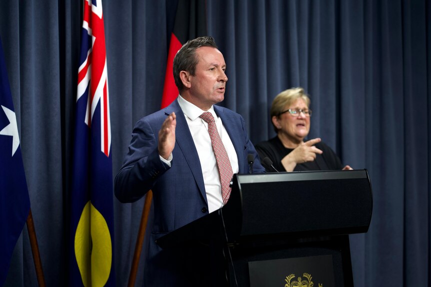Premier Mark McGowan at a podium with a woman behind him.