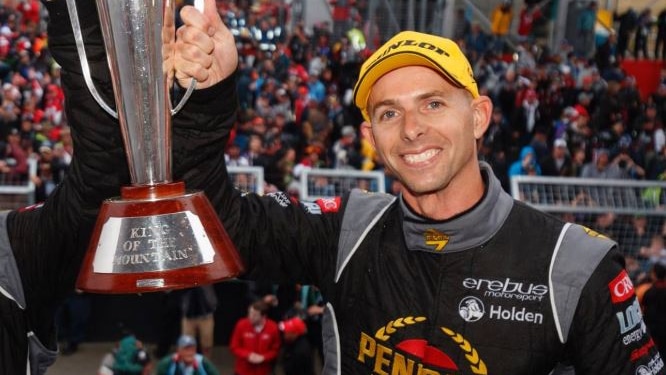 Supercars driver Luke Youlden smiles as he holds up a trophy
