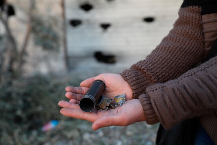 A child's hands hold an empty bullet shell.
