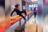 A still image from a prank video, showing a jewellery store employee jumping over a counter to chase a would-be thief.