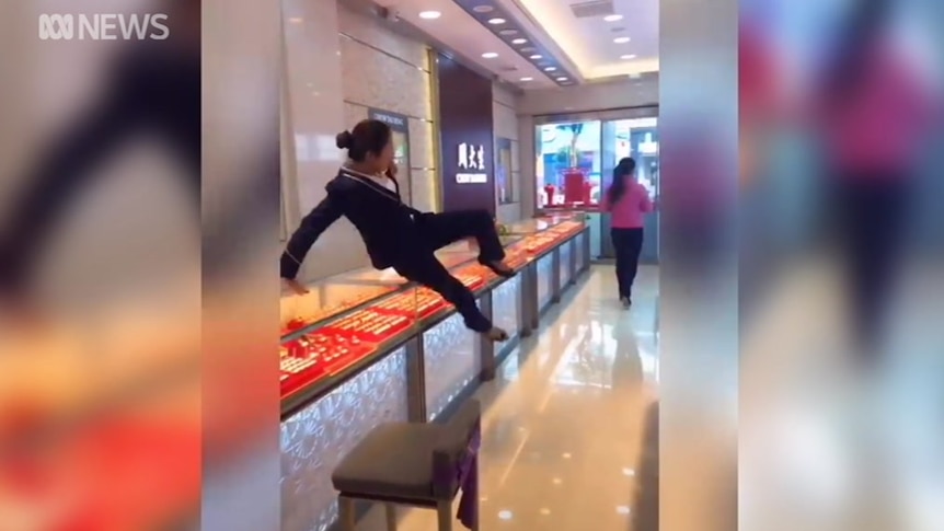 A still image from a prank video, showing a jewellery store employee jumping over a counter to chase a would-be thief.