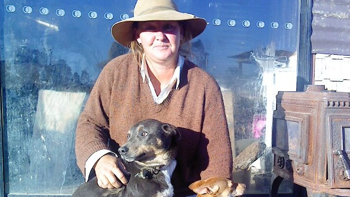 Queensland drover Jen McClelland kneeling with two dogs with a hat on