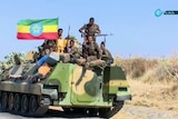 Ethiopian military sitting on an armoured personnel carrier next to a national flag