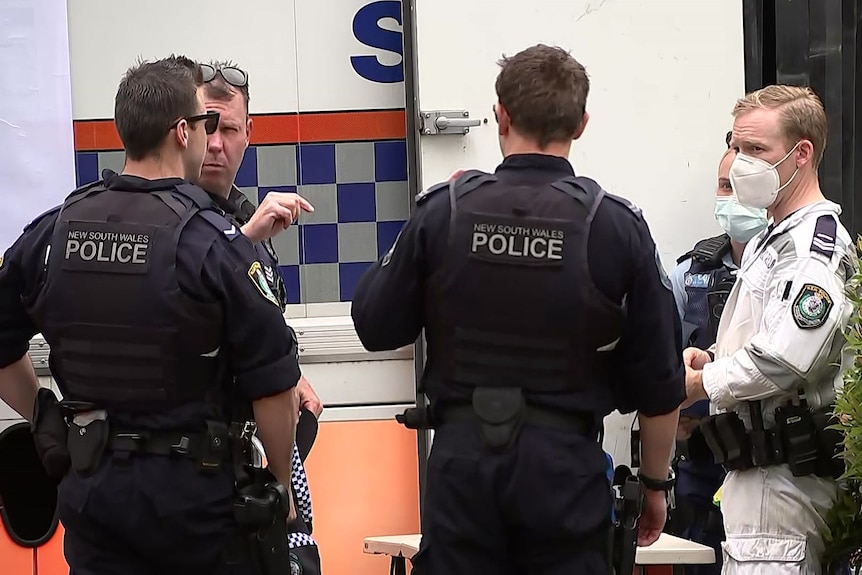 a group of police men and emergency personnel next to a van