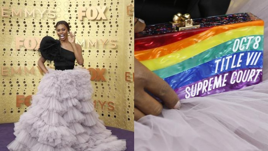 Laverne Cox wears a lilac and black dress as she smiles on the Emmy Awards purple carpet with a gold backdrop.