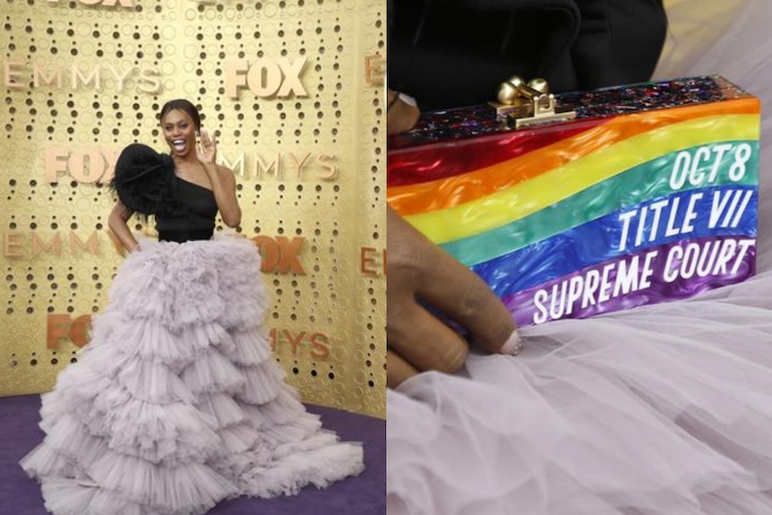 Laverne Cox wears a lilac and black dress as she smiles on the Emmy Awards purple carpet with a gold backdrop.