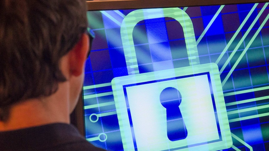 A man works at a computer with a padlock graphic on the screen.