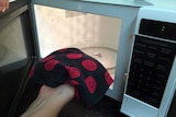 A wheat bag being put in a microwave.