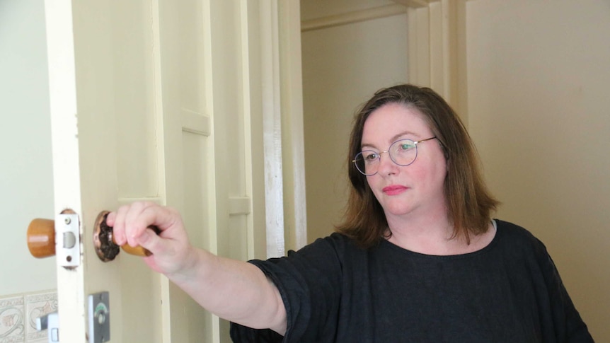 Jacki Whittaker stares into a room after opening a door.