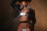 Beyonce wearing a black jacket, black cowboy hat, and big silver earrings