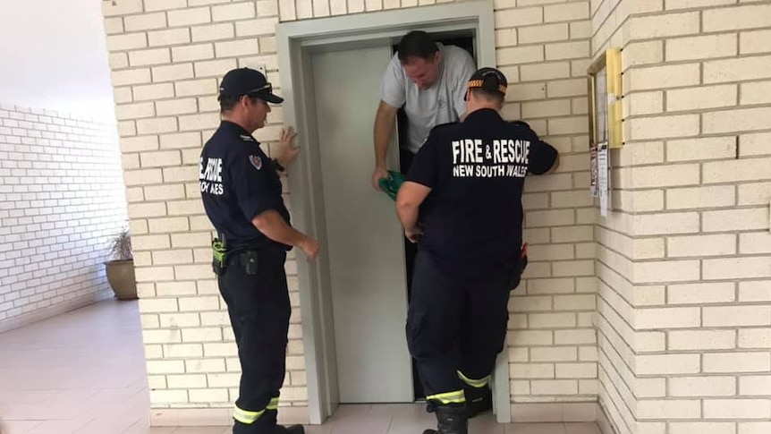 A man being helped from his apartment block lift by firefighters