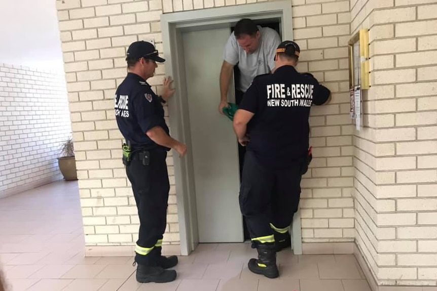 A man being helped from his apartment block lift by firefighters