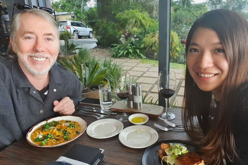 Man and woman smile while taking a selfie at lunch.