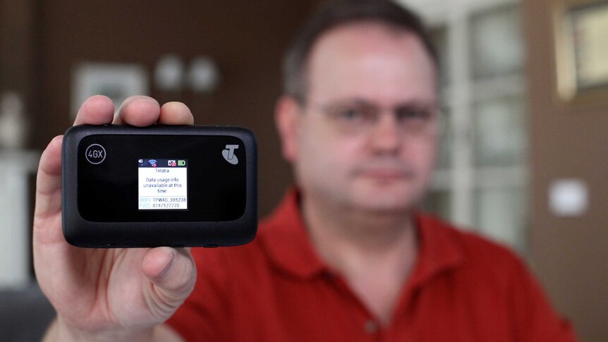 Darren Haymes holds up his Telstra dongle which shows data usage is unavailable.