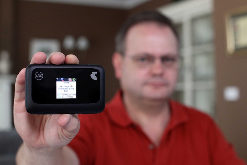 Darren Haymes holds up his Telstra dongle which shows data usage is unavailable.