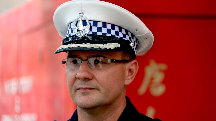 NT Police Commissioner Reece Kershaw stands with a sad expression on his face, in police uniform and hat.