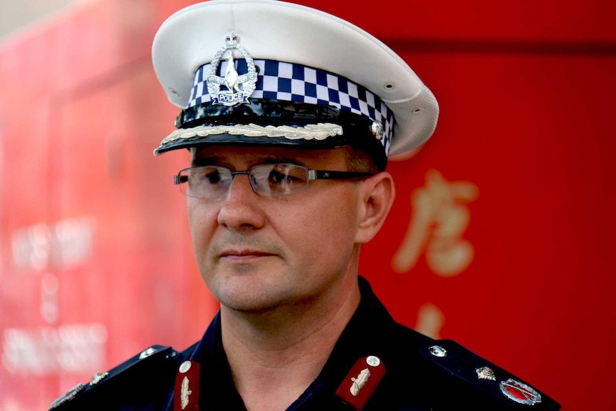 NT Police Commissioner Reece Kershaw stands with a sad expression on his face, in police uniform and hat.