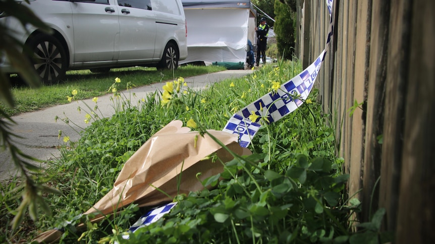 Flowers and police tape in scene of crime