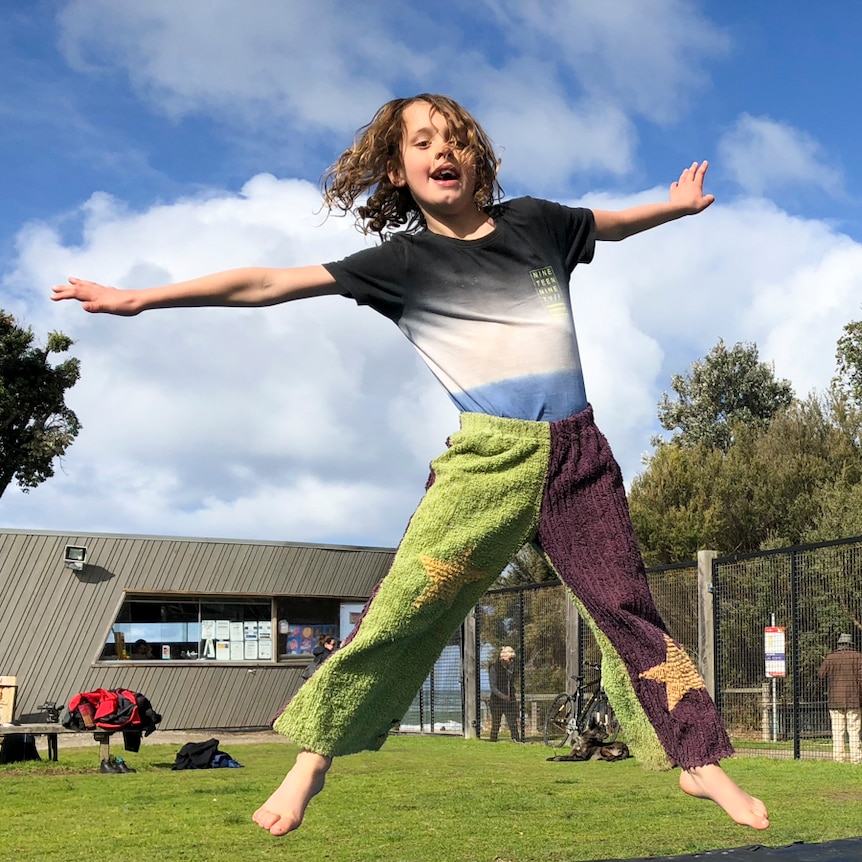 child jumping high in star jump shape on outdoor inground trampoline