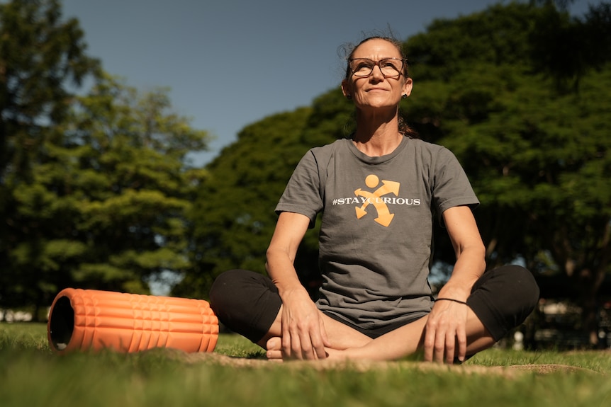 Health coach Nat Evans joins an exercise class in a park.