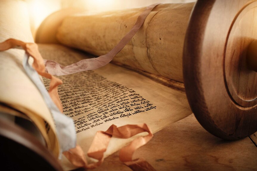 A Torah scroll is opened with ribbons draped across it.