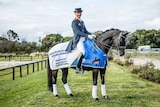 Dressage rider Brett Parbery mounted on his horse in an equestrian training facility.