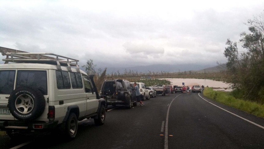 Cars lined up on the road, which is cut by floodwaters in the wake of Cyclone Yasi.