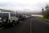Cars lined up on the road, which is cut by floodwaters in the wake of Cyclone Yasi.