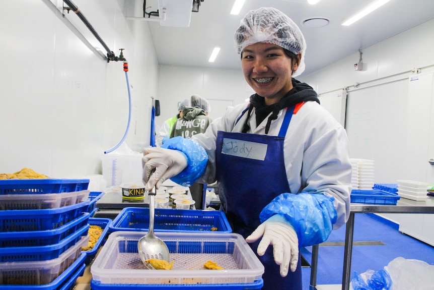 A Taiwanese young woman smiles at the camera in a sea urchin factory.