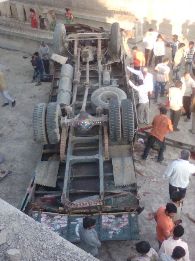 People surround an upturned truck.