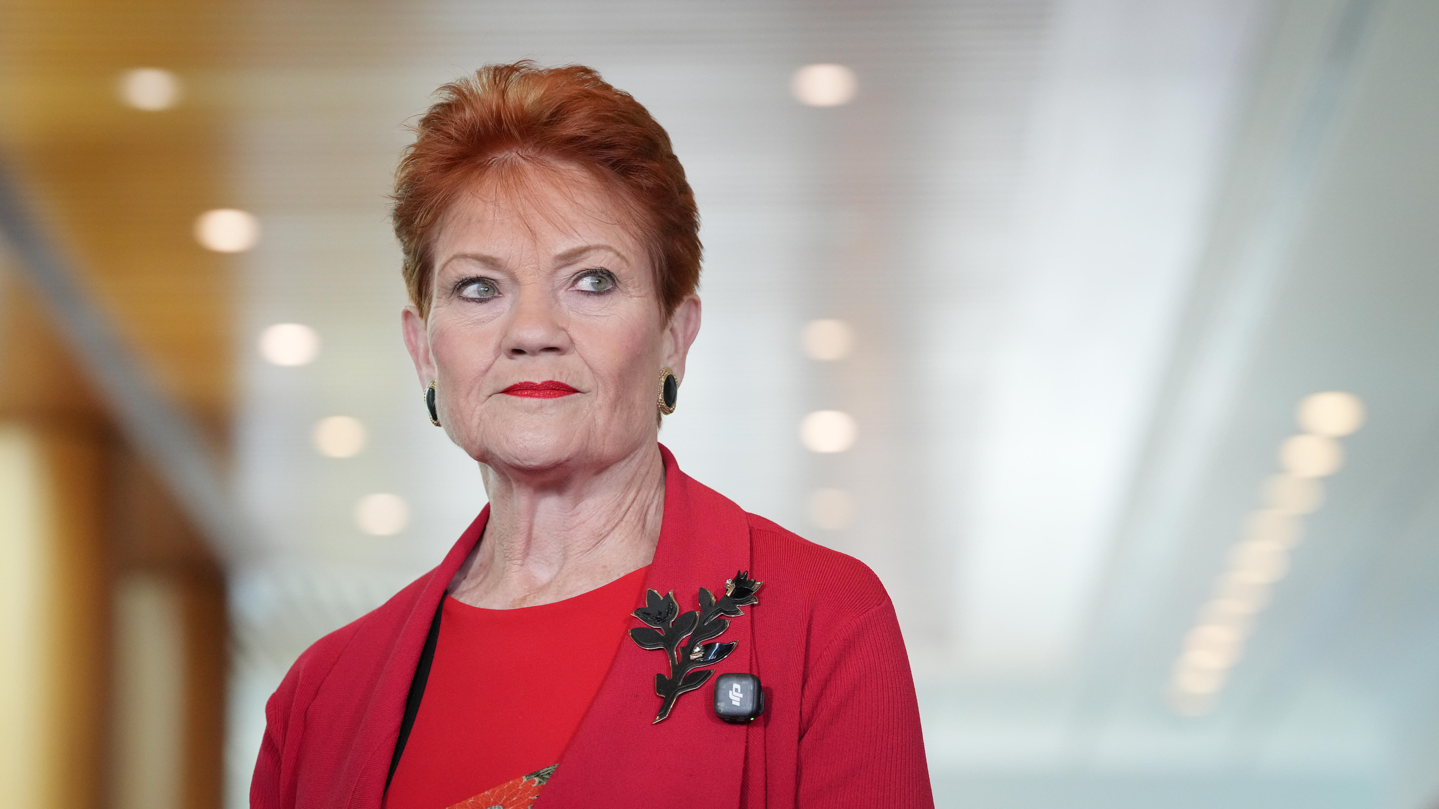 Pauline looks serious while wearing a red top and jacket