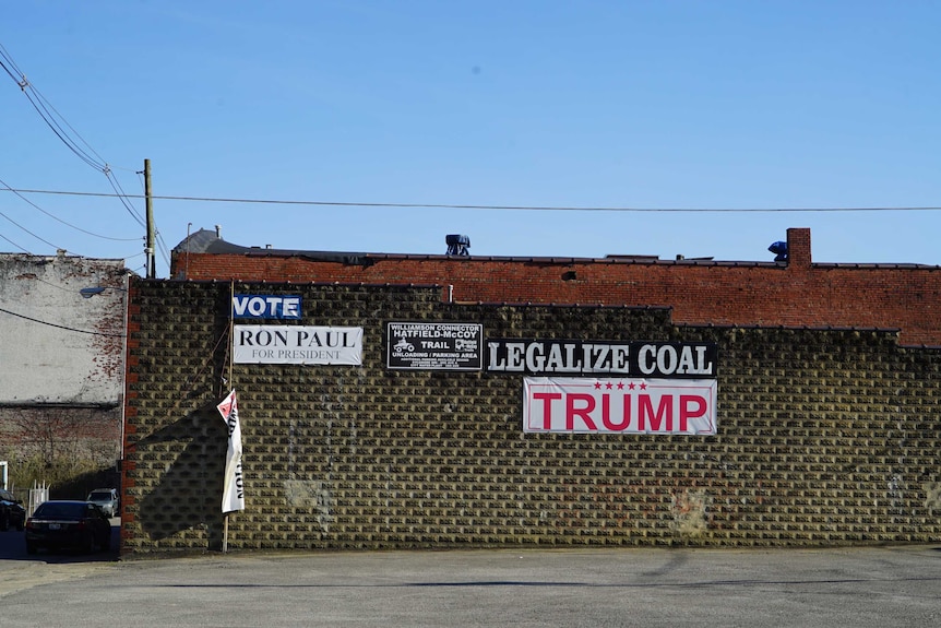 A "Trump" sign hangs on a business near a sign reading "legalize coal" and "Vote Ron Paul for president"