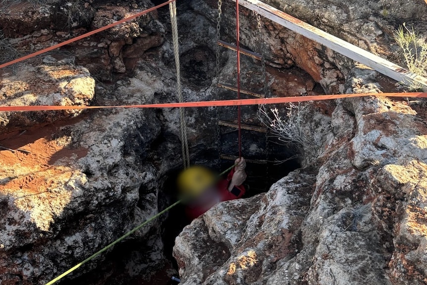 Emergency services personnel work to free a woman from a cave.