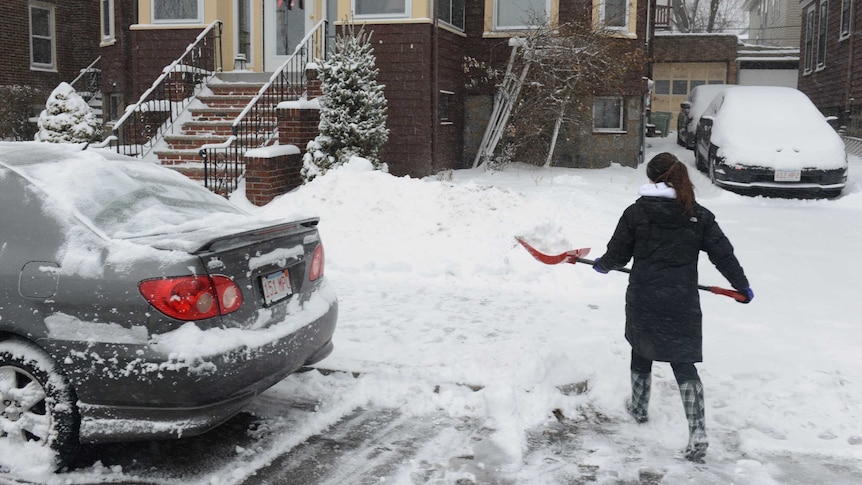 A woman shovels snow on Bayswater Street in East Boston, Massachusetts.