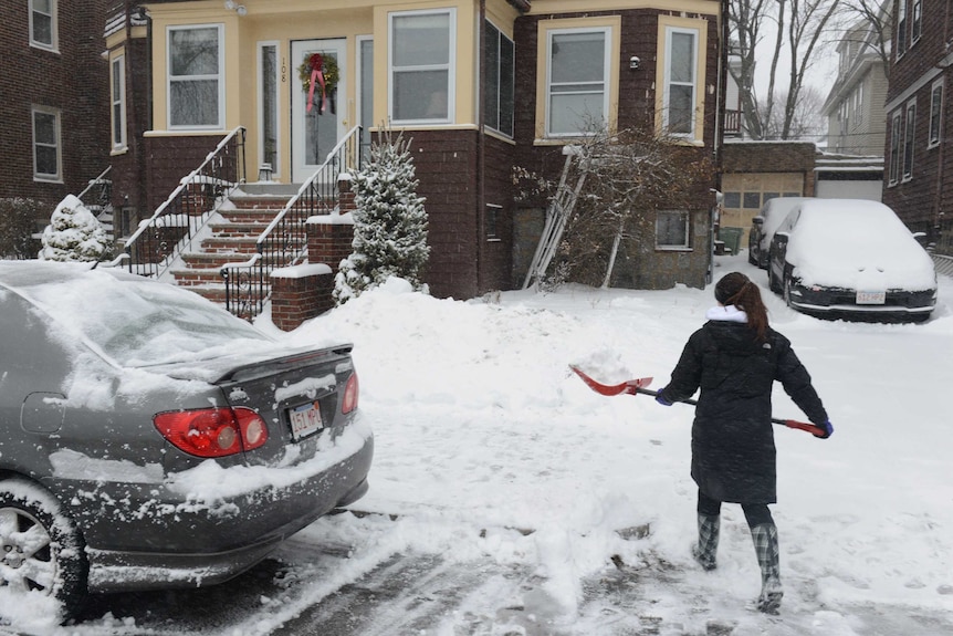 A woman shovels snow on Bayswater Street in East Boston, Massachusetts.
