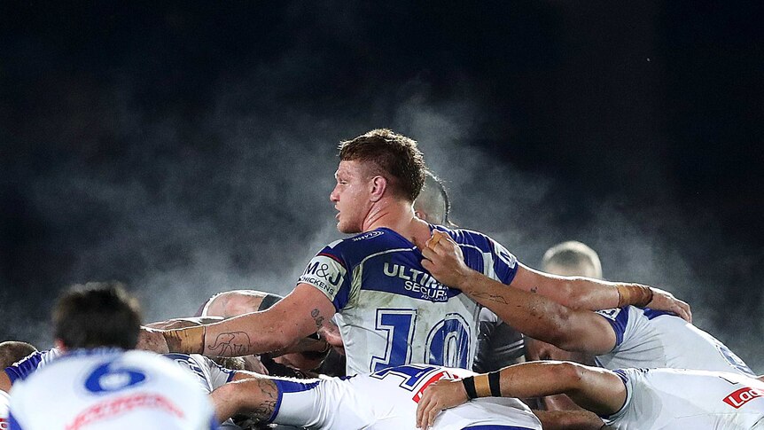 A man is embraced by teammates as he packs a rugby league scrum